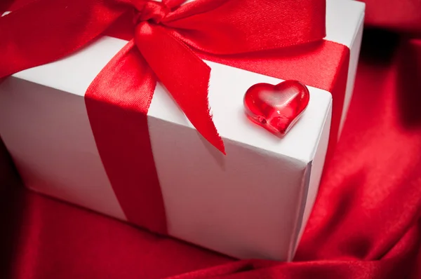 Valentines gift boxes tied with a red satin ribbon bow on red satin background — Stock Photo, Image