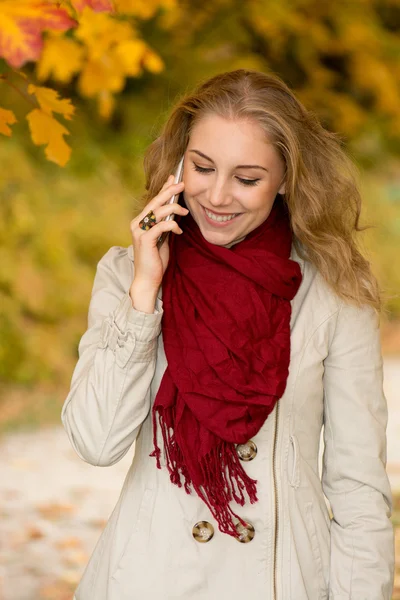 Gelukkig jonge vrouw op mobiele telefoon in de herfst park — Stockfoto