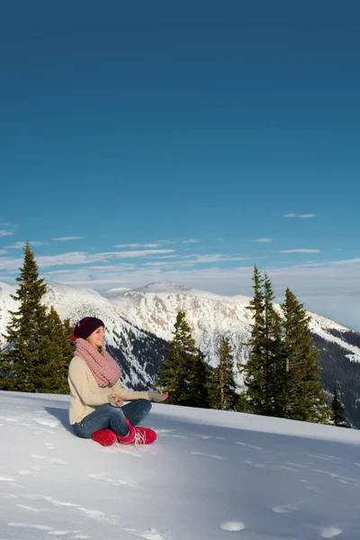 Genç bir kadın lotus pozisyonunda kar üzerinde meditates. — Stok fotoğraf