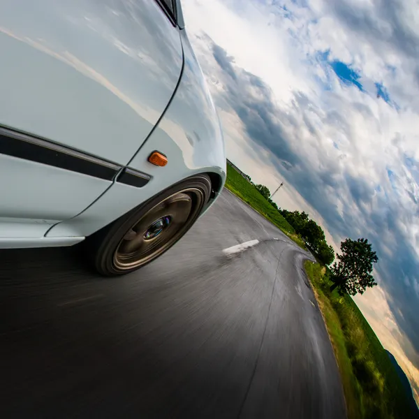 Jazda w krzywej - widok przodu biały samochód szybkiej jazdy. — Zdjęcie stockowe