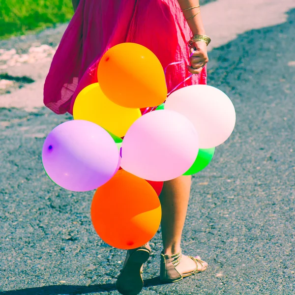 Chica sosteniendo montón de globos de aire de colores — Foto de Stock