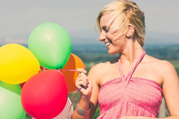 Smiling girl holding bunch of colorful air balloons — Stock Photo, Image