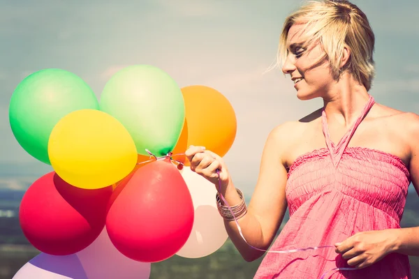 Smiling girl holding bunch of colorful air balloons — Stock Photo, Image