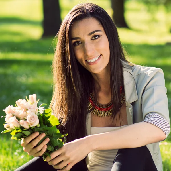 Frau lächelt und zeigt Blumenstrauß — Stockfoto