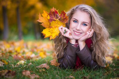 Woman lying on autumn leaves, outdoor portrait clipart