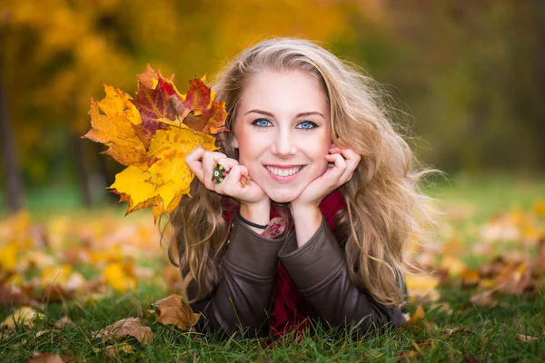 Frau auf Herbstblättern liegend, Außenporträt — Stockfoto