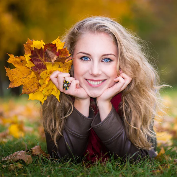 Frau auf Herbstblättern liegend, Außenporträt — Stockfoto