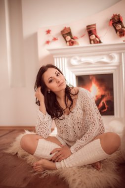 şömine ve Noel ağacının yanında oturan güzel genç kız