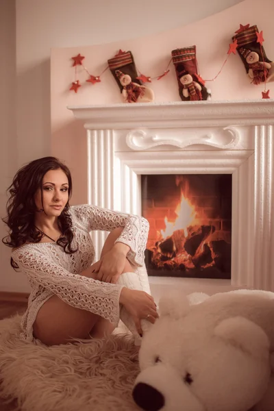 Sexy chica sentada junto a la chimenea y el árbol de Navidad —  Fotos de Stock