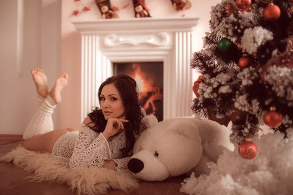 Sexig tjej ligga bredvid den öppna spisen och julgran — Stockfoto