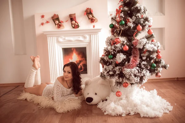 Sexy Mädchen liegt neben dem Kamin und Weihnachtsbaum — Stockfoto