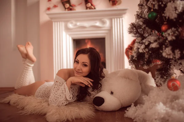 Sexy Mädchen liegt neben dem Kamin und Weihnachtsbaum — Stockfoto