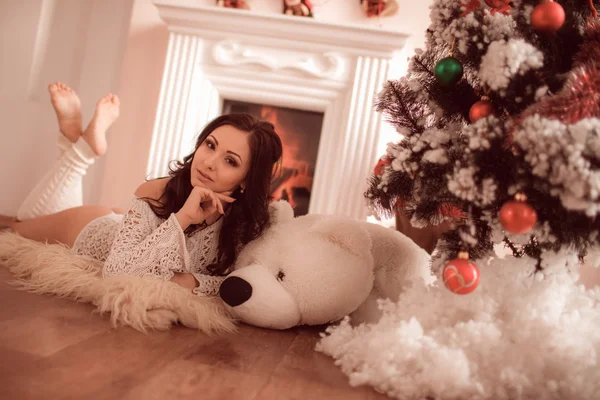 Sexy chica acostada junto a la chimenea y el árbol de Navidad — Foto de Stock