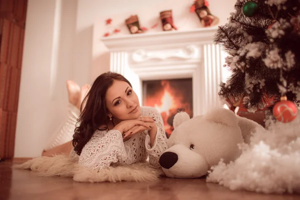 性感的女孩躺在壁炉和圣诞树旁边 — 图库照片