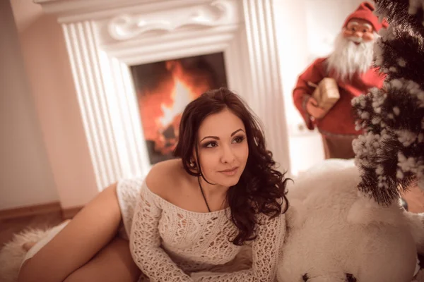 Sexy Mädchen liegt neben dem Kamin und Weihnachtsbaum — Stockfoto