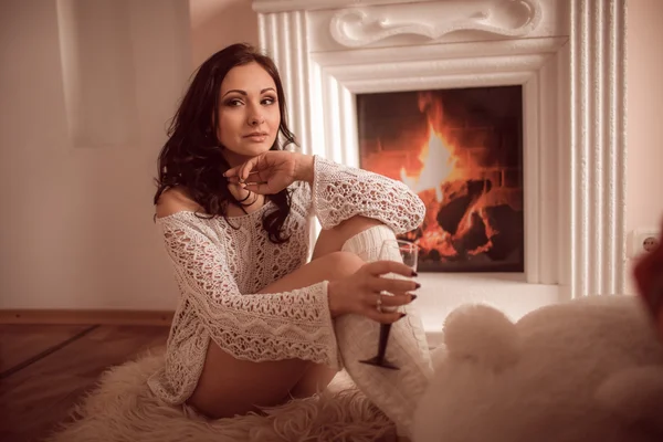 Sexy chica sentada junto a la chimenea y el árbol de Navidad — Foto de Stock