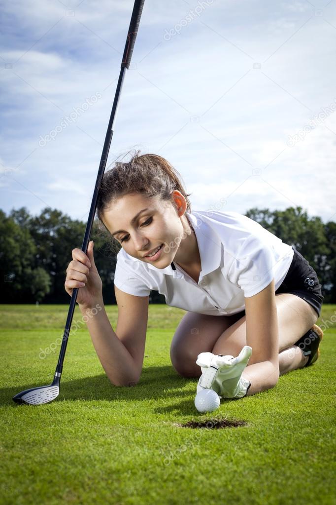 Pretty girl playing golf on grass