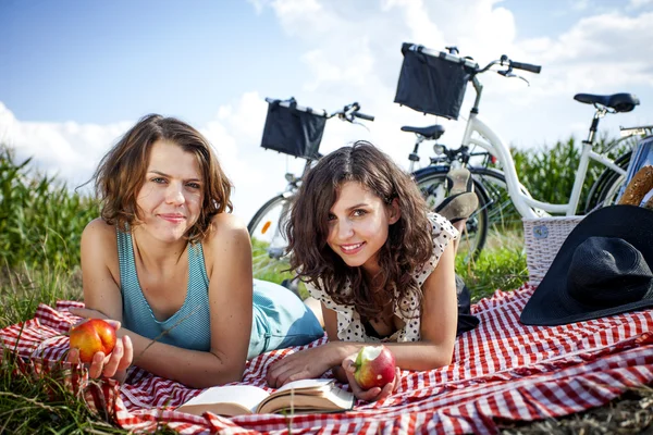 Dos chicas guapas hacen un picnic, leyendo un libro — Foto de Stock