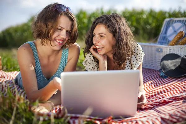 Deux jolies filles font un pique-nique et vérifient l'ordinateur — Photo