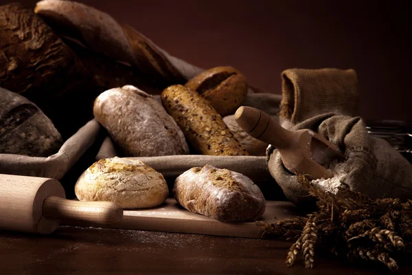 Tahta masada taze ekmek ve buğday. — Stok fotoğraf