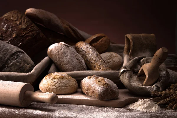 Pão fresco e trigo na mesa de madeira — Fotografia de Stock