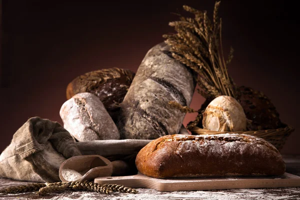 Свежий хлеб и пшеница на деревянном столе — стоковое фото