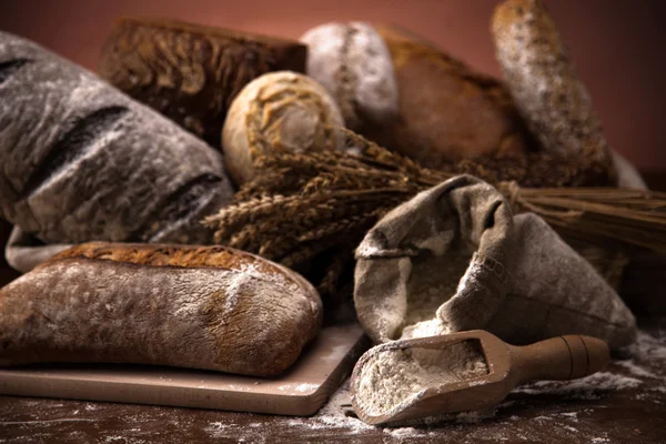 Friss kenyér és búza a fa asztalon — Stock Fotó