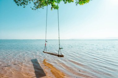 Wooden swing on the beach and the evening sun