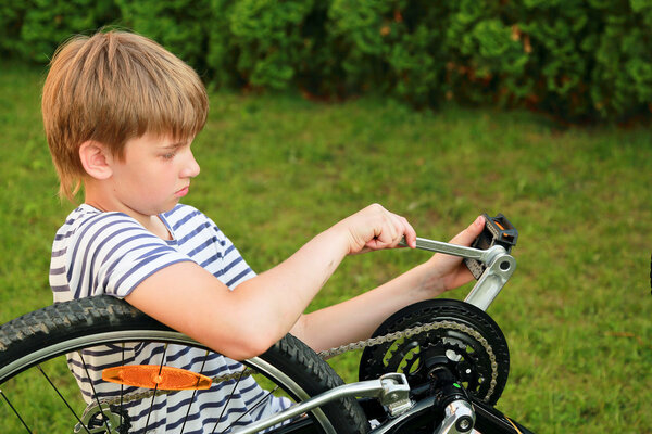 Мальчик чинит велосипед
