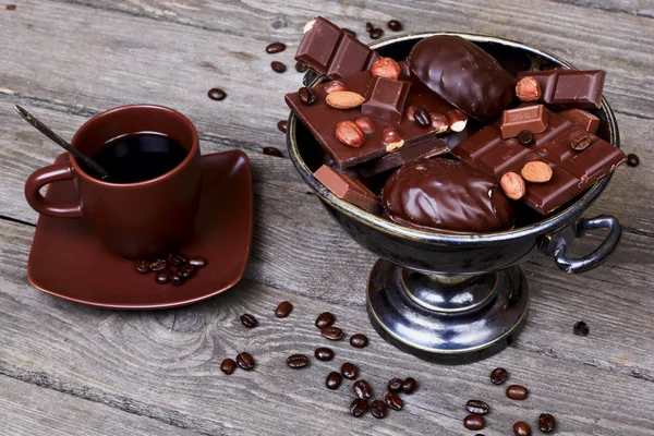 Vaso con cioccolato, noci e caffè su sfondo grigio in legno — Foto Stock