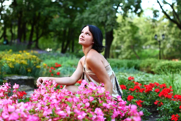 Krásná dívka v parku s barevnými květy — Stock fotografie