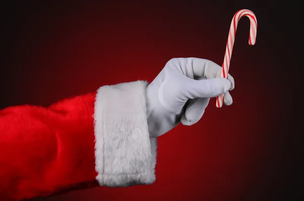 Santa Claus mano sosteniendo bastón de caramelo —  Fotos de Stock