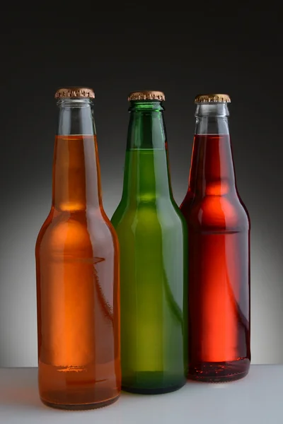 Frisdrank flessen op licht aan donkere achtergrond — Stockfoto