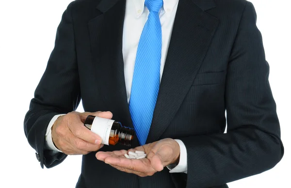 Empresário derramando pílulas em sua mão — Fotografia de Stock