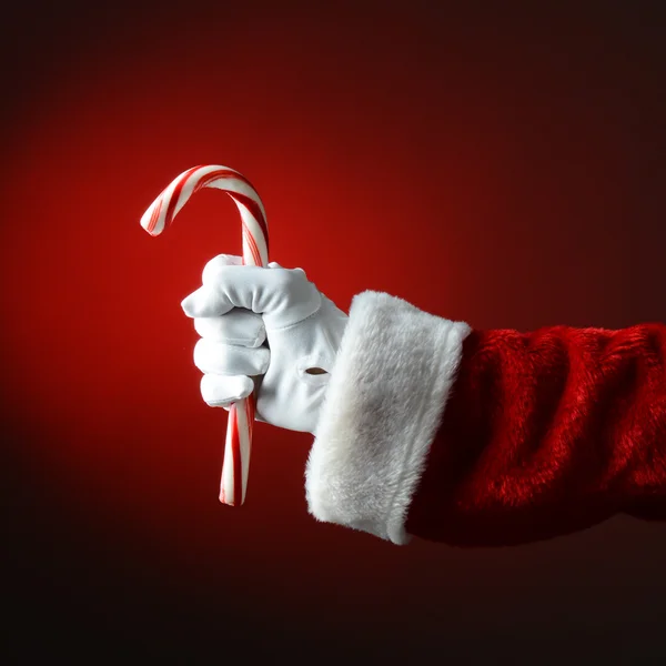 Santa Claus sosteniendo gran bastón de caramelo sobre una luz a rojo oscuro Ba —  Fotos de Stock