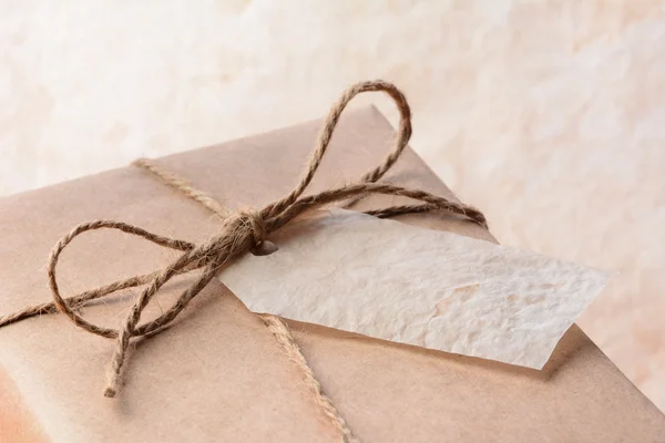 Braunes Papier verpackt Paket mit Geschenkanhänger — Stockfoto