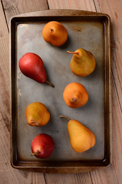 Bosc and Red Pears on Baking Sheet on Wood Table — Stock Photo, Image