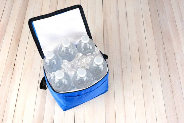 六瓶塑料水瓶和冰块在白色木桌上的可折叠冷却器中的高角度视图 具有复制空间的水平格式 — 图库照片