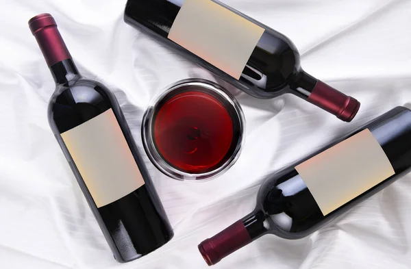 Wine Glass Center Three Bottles Laying Sides White Fabric Surface — Stock Photo, Image