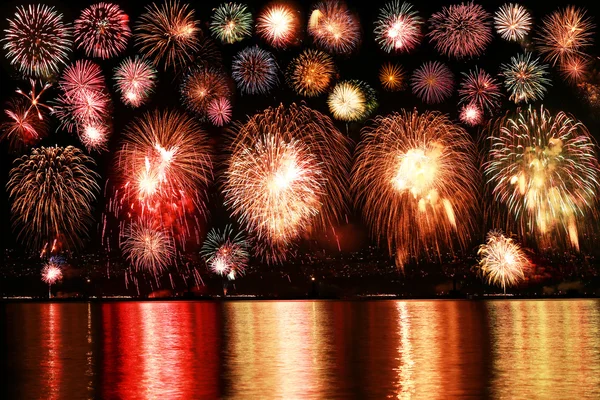 Coloridos fuegos artificiales reflejan desde el agua — Foto de Stock