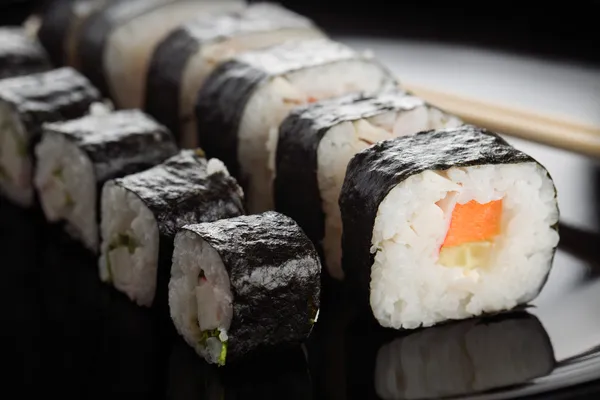 Rolos de sushi em prato preto — Fotografia de Stock