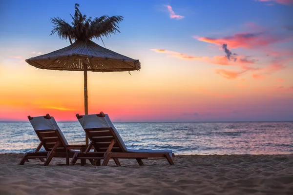 Vivid sunrise on a beautiful sandy beach with sunshade — Stock Photo, Image