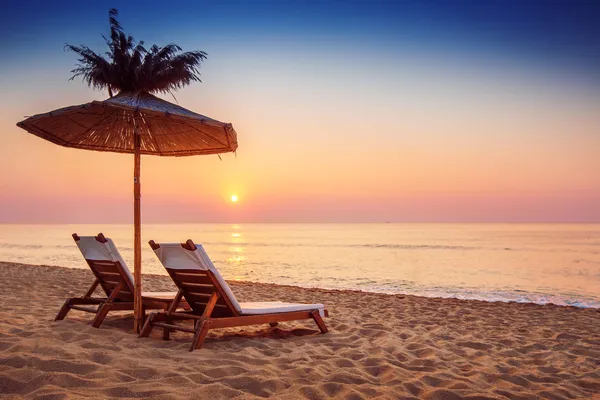 Яркий восход солнца на прекрасном песчаном пляже с зонтиком — стоковое фото