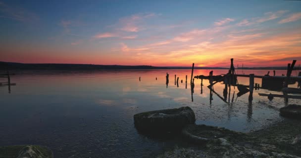 劇的な日没の間の海の湖と古い木製の桟橋の風景 — ストック動画