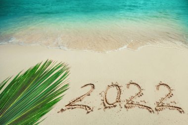 Kumsaldaki Yumuşak Mavi Okyanus Dalgası 'nın arka planı. Kumda yeni yıl 2022 metni