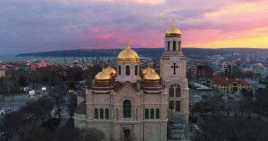 Bulgaristan 'ın Varna kentindeki Varsayımın Katedrali ve 4k video klibinde renkli günbatımı hava manzarası