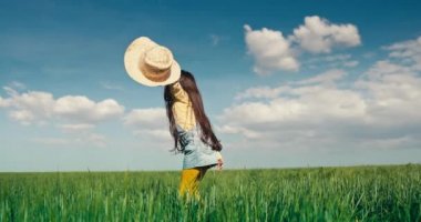 Yeşil arazi ve mutlu çiftçi kız hasır şapkayla oynuyor.