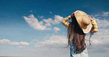 Yeşil arazi ve mutlu çiftçi kız hasır şapkayla oynuyor.