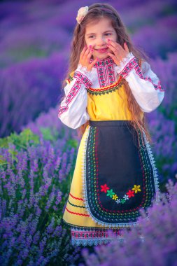 Hasat ve gün batımında lavanta tarlasında geleneksel Bulgar folklor kostümlü güzel kız