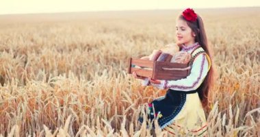 Beautiful girl woman in traditional Bulgarian folklore dress holding wicker crate with homemade breads in wheat field